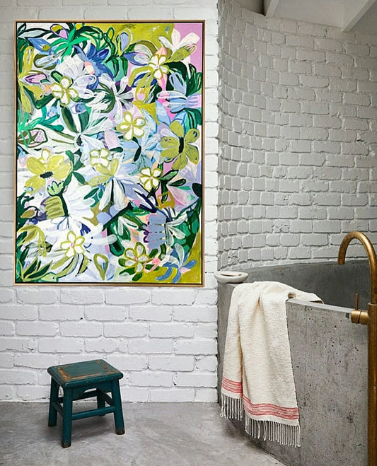 Bathroom with a colorful floral painting on a white brick wall, a bathtub with a towel, and a small stool.