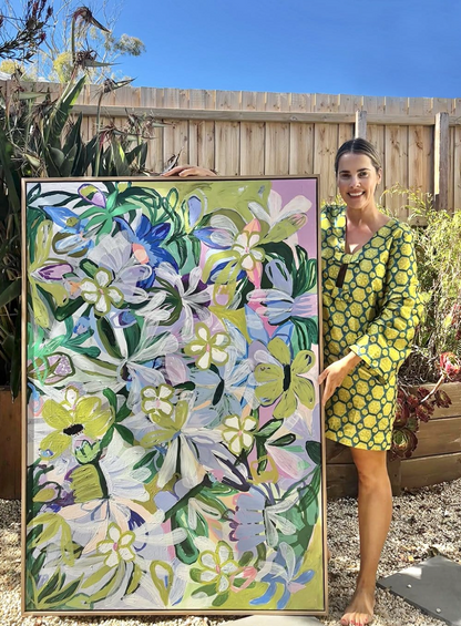 Woman in a yellow dress standing next to a large floral painting outdoors.