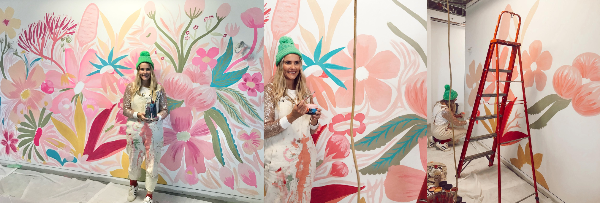 Woman standing in front of a colorful floral mural with a ladder and art supplies.