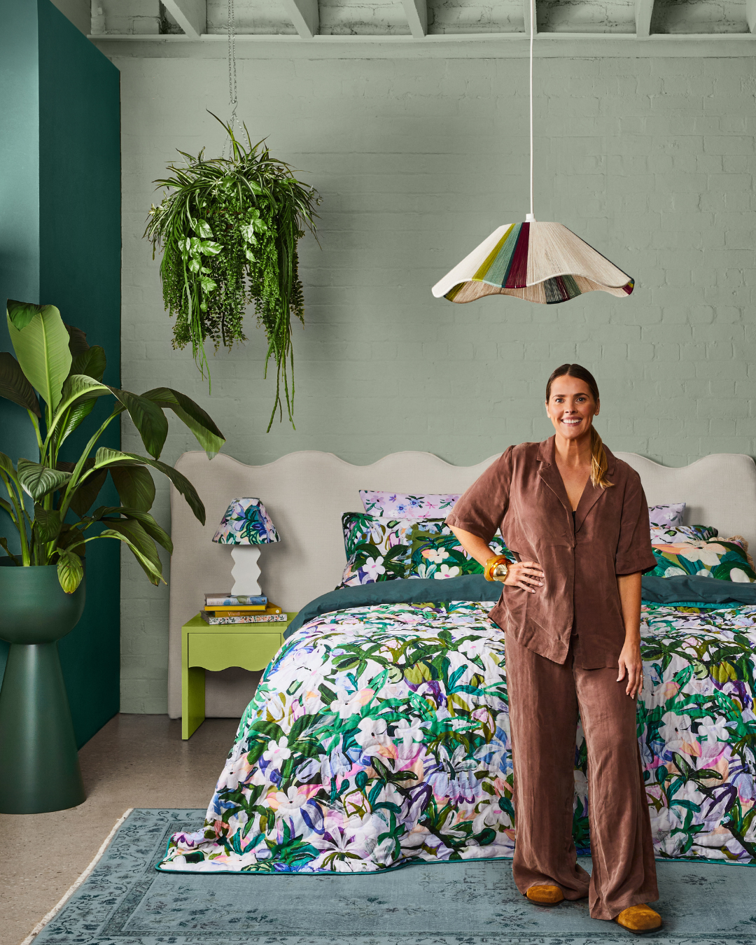 Woman standing in a bedroom with floral bedding and coluorful decor