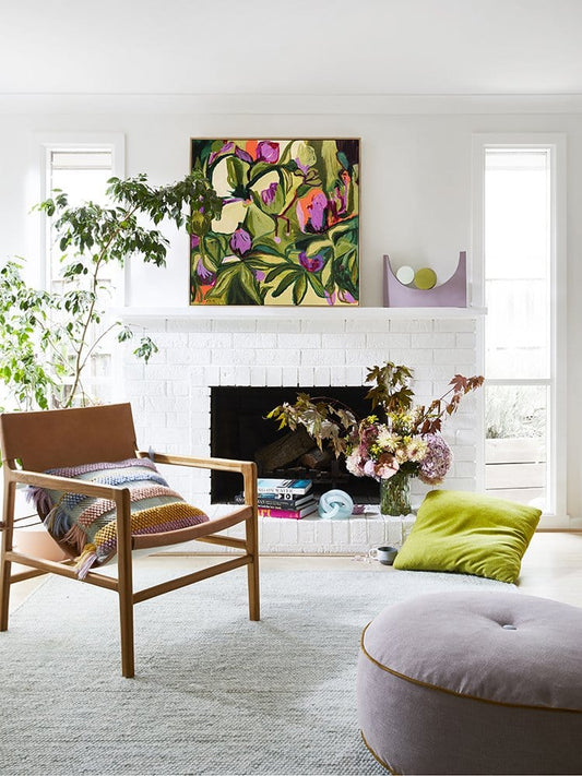 Modern living room with a fireplace, floral artwork, and decorative items.